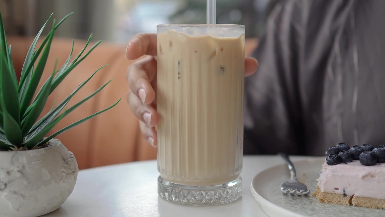 Kvinne som drikker iskaffe på en kafé.