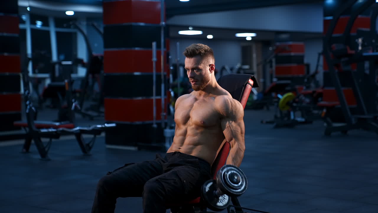 Athletic man with dumbbells. Handsome muscular man working out with dumbbells
