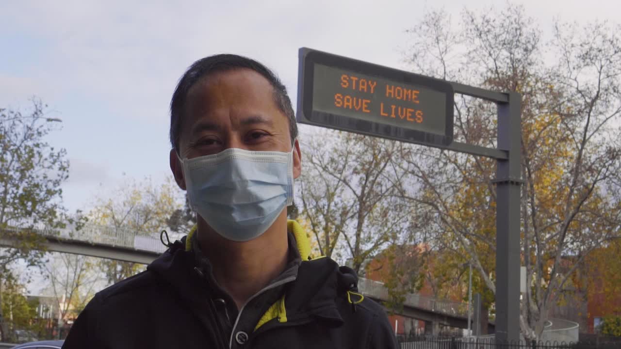 A sign reads 'Stay Home, Save Lives' behind a man wearing a mask during the coronavirus outbreak