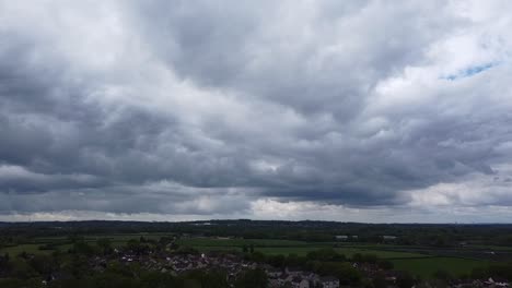 a heavy grey cloud about to start raining hard in a countryside town in the south of england