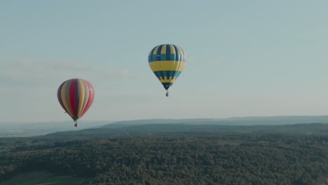 4k-Antenne-Zwei-Heißluftballons,-Die-An-Einem-Schönen-Tag-über-Den-Wald-Fliegen