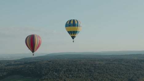 4k aerial two hot air balloons flying over the forest on a beautiful day