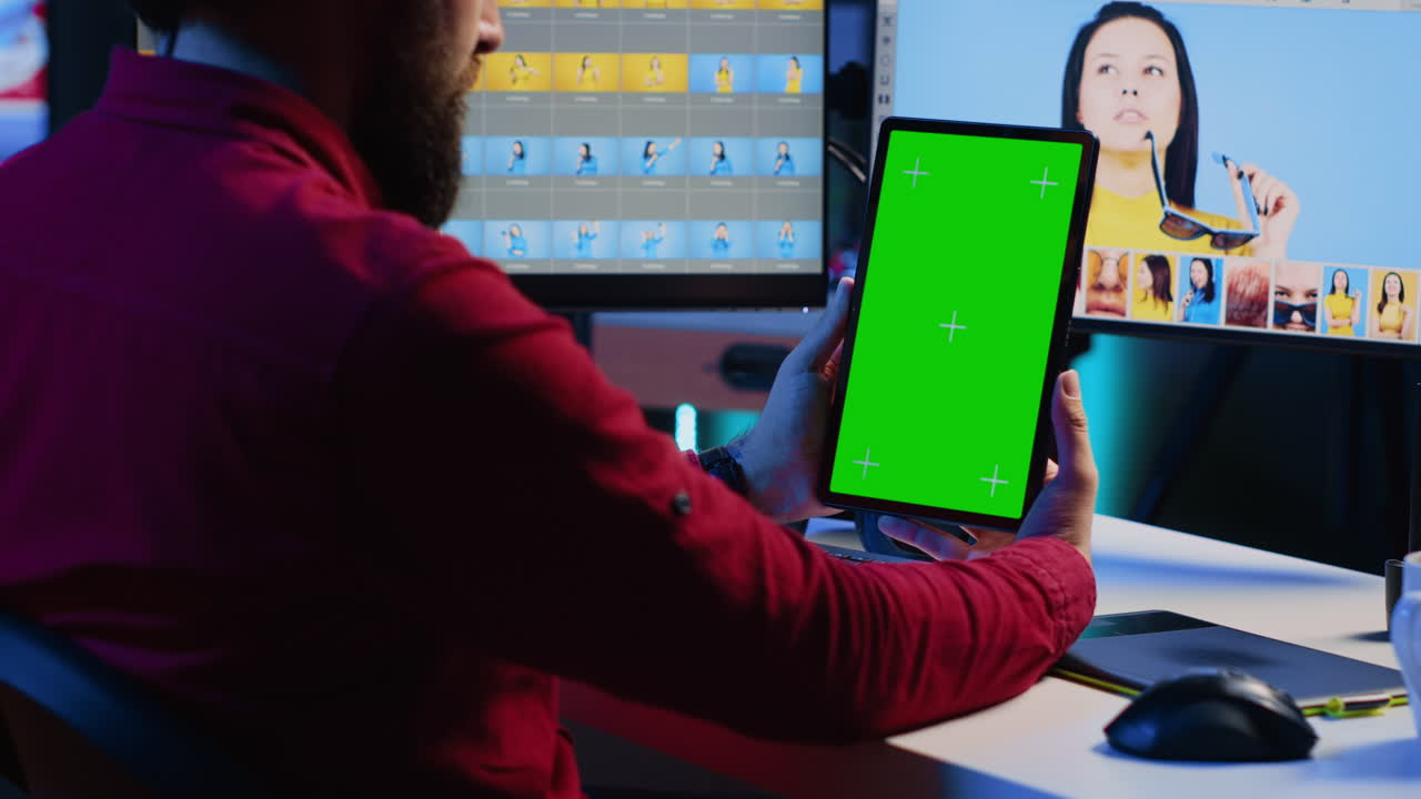 Photo editor learning from tutorial on green screen tablet while working in production company