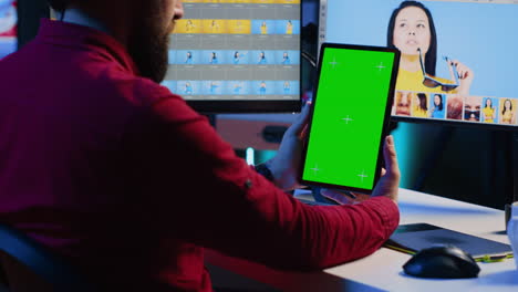 Photo-editor-learning-from-tutorial-on-green-screen-tablet-while-working-in-production-company