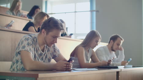 Grupo-Multiétnico-De-Estudiantes-Que-Utilizan-Teléfonos-Inteligentes-Durante-La-Conferencia.-Jóvenes-Que-Usan-Las-Redes-Sociales-Mientras-Estudian-En-La-Universidad.