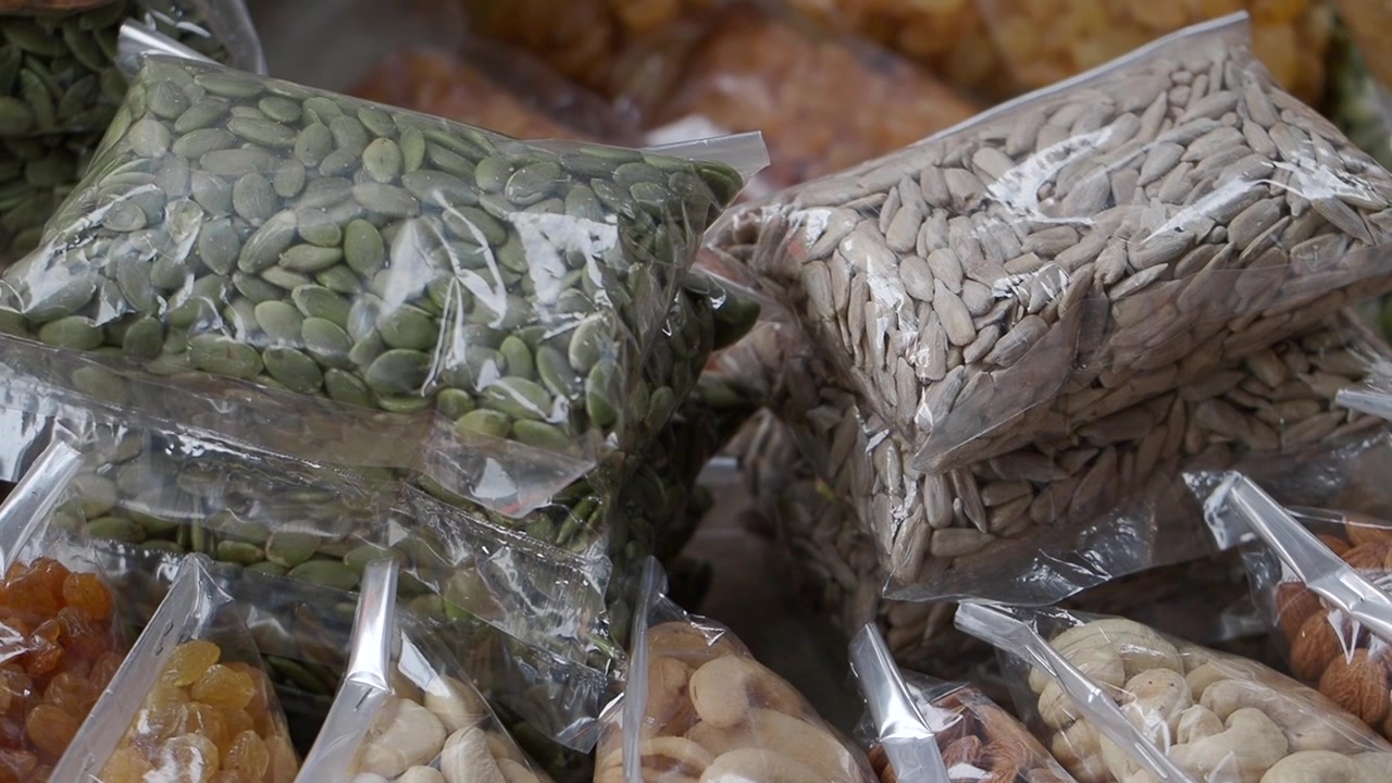 Assorted Nuts and Seeds in Plastic Bags at a Market