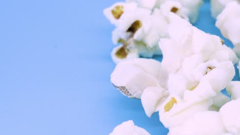 Extreme-close-up-view-of-popcorn-rotating-on-blue-surface,-close-up-view-in-4k