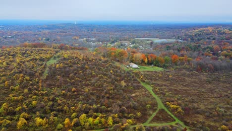 Una-Panorámica-Lateral-Aérea-De-La-Zona-Rural-De-Nueva-York-En-Otoño-Durante-El-Pico-De-Follaje-Con-Colinas-Y-Valles