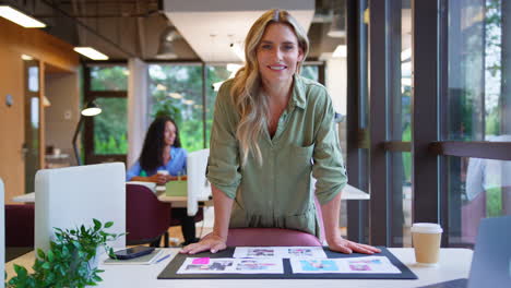 Portrait-Of-Mature-Businesswoman-Standing-In-Office-Approving-Or-Checking-Proofs-Or-Design-Layouts