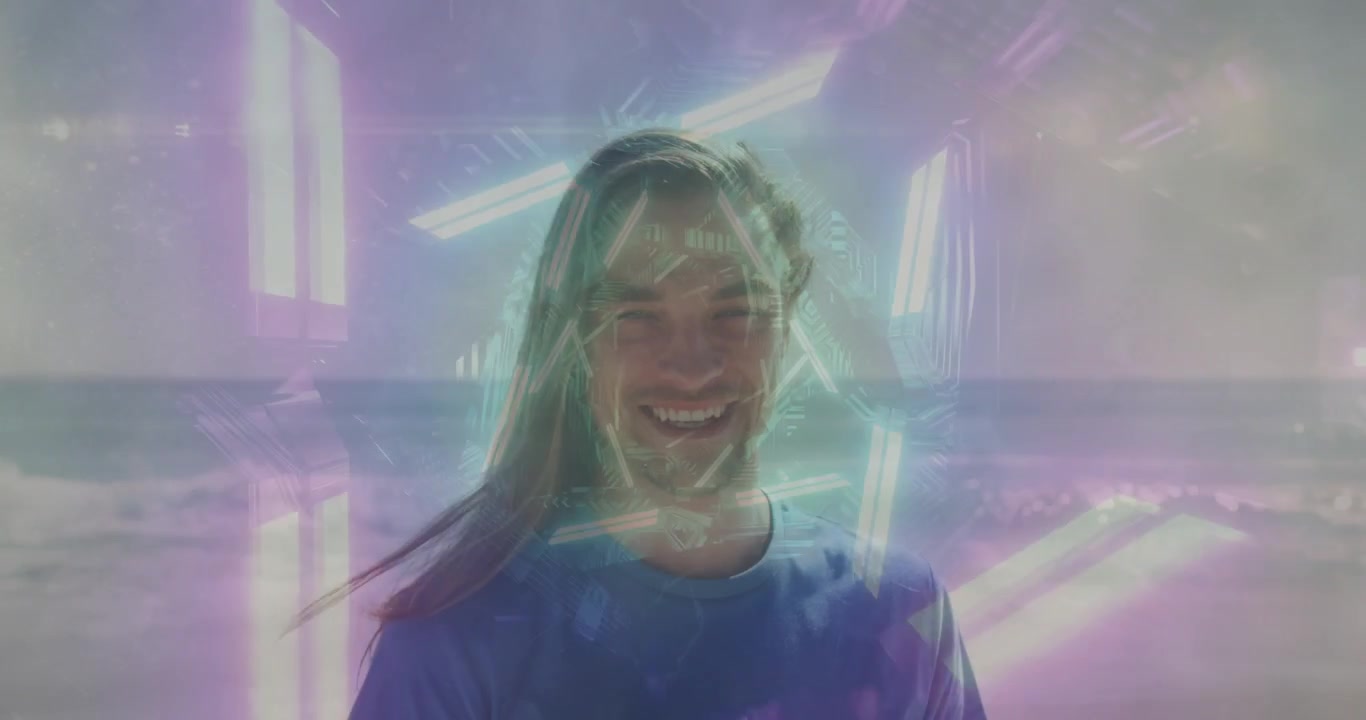 Homem em pé na praia enquanto uma sobreposição de néon aparece, formando um halo hexagonal na cabeça, sorrindo, mostrando RA.