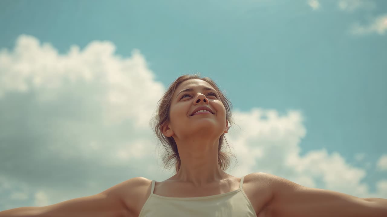 Raising arms adult woman bathing in daylight lifting to blue sky with clouds wearing sleeveless top