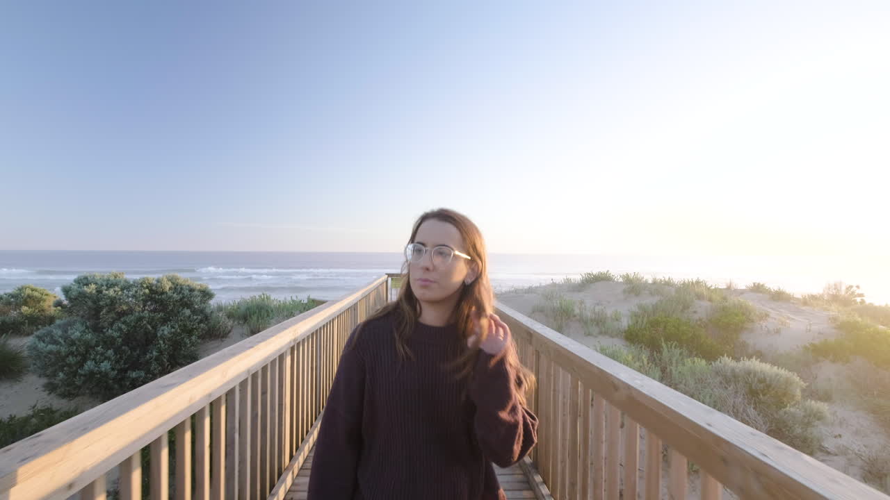 웃고 웃는 해변에서 부두를 따라 걷는 어린 소녀