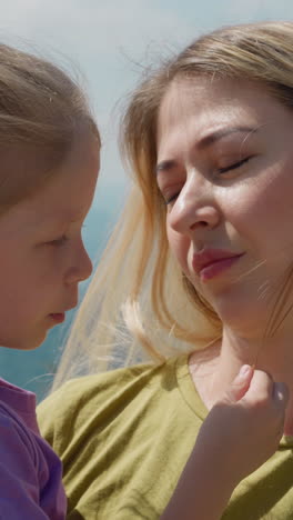 attentive blonde mother holds little daughter in arms listening to story against modern poma lift and foggy mountains at resort closeup slow motion