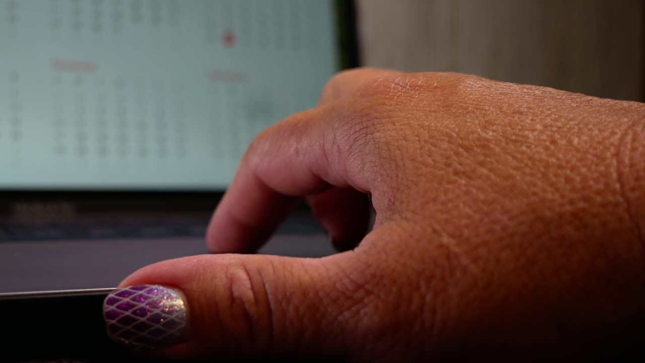 cerca de las manos de una mujer mayor escribiendo en el teclado de una computadora portátil, la pantalla apenas es visible