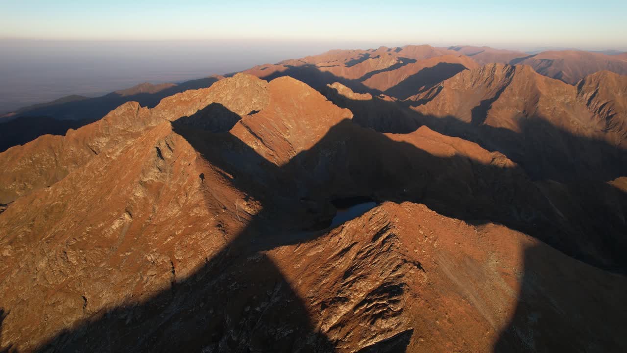 Sunlit mountain range casting dramatic shadows at sunrise, evoking tranquility , aerial view