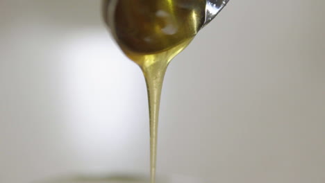 Close-up-of-honey-dripping-off-spoon-in-slow-motion