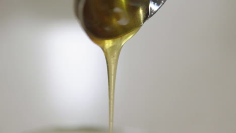 close up of honey dripping off spoon in slow motion