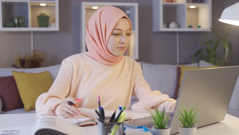 Female-muslim-student-studying-using-laptop-and-books.