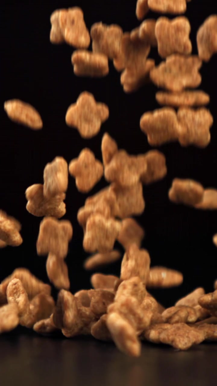Slow Motion of Golden Brown Cereal Pieces Falling on Black Background