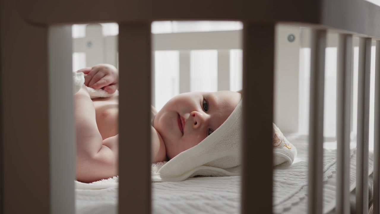 Newborn baby rests peacefully in crib gazing upwards with innocent curiosity creating a serene and