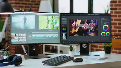 empty office workspace with dual monitors displaying a video editing timeline