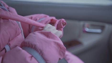 girl in pink winter jacket sits in modern car salon closeup