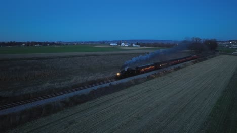 A-Drone-Night-View-of-a-Steam-Passenger-Train-Approaching-on-a-Single-Track-Traveling-Thru-Farmlands