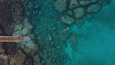 Aerial-footage-of-a-female-swimmer,-going-for-the-pier