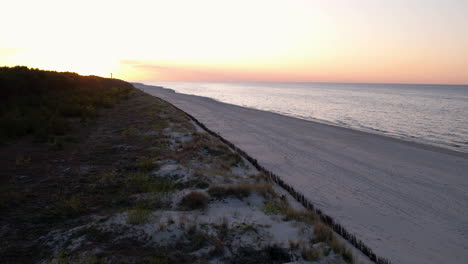 Slow-motion-dolly-push-in-along-beach-at-blue-golden-hour,-beautiful-sandy-coastal-dunes