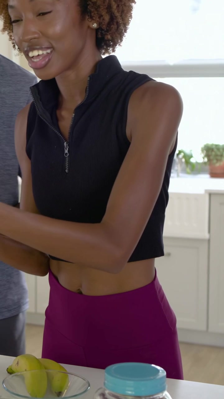 Video verticale: Donna in abiti da allenamento che parla durante una chiacchierata in cucina, porgendo una ciotola di frutti di bosco.