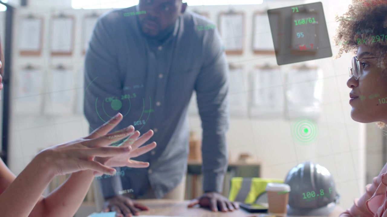 Seated lead designer gesturing, causing green holo UI projecting between participants for planning