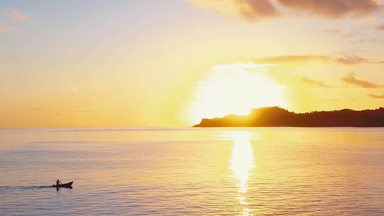 medium shot of Fisherman paddling back home during sunset after a long day of fishing in the Comoros, Africa.
