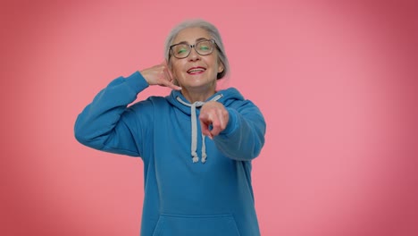 Elderly-granny-gray-haired-woman-looking-at-camera-doing-phone-gesture-like-say-hey-you-call-me-back