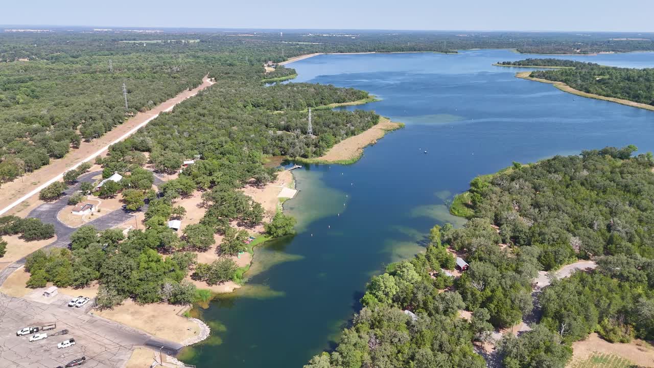 dando vueltas a la derecha por encima de una amplia vista del lago con área de rampa para botes, playa, muelle de pesca a la izquierda