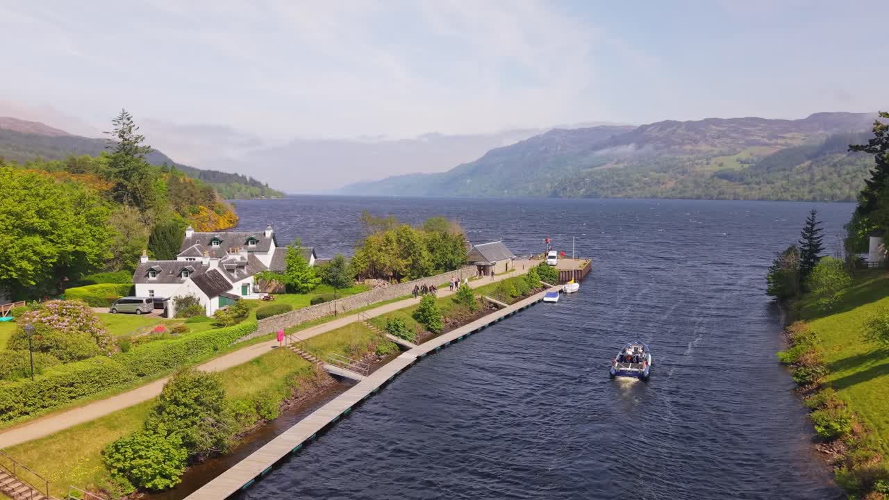 Drone captures a boat navigating the Caledonian Canal at Fort Augustus, heading toward Loch Ness through the canal locks and lush Highland scenery