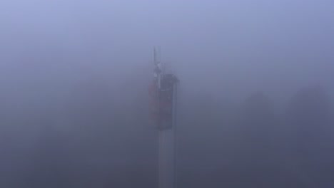 Antenas-De-Comunicación-En-Torre-De-Agua-En-Niebla-Espesa-Con-Poca-Visibilidad,-Inclinación-Aérea-Hacia-Abajo