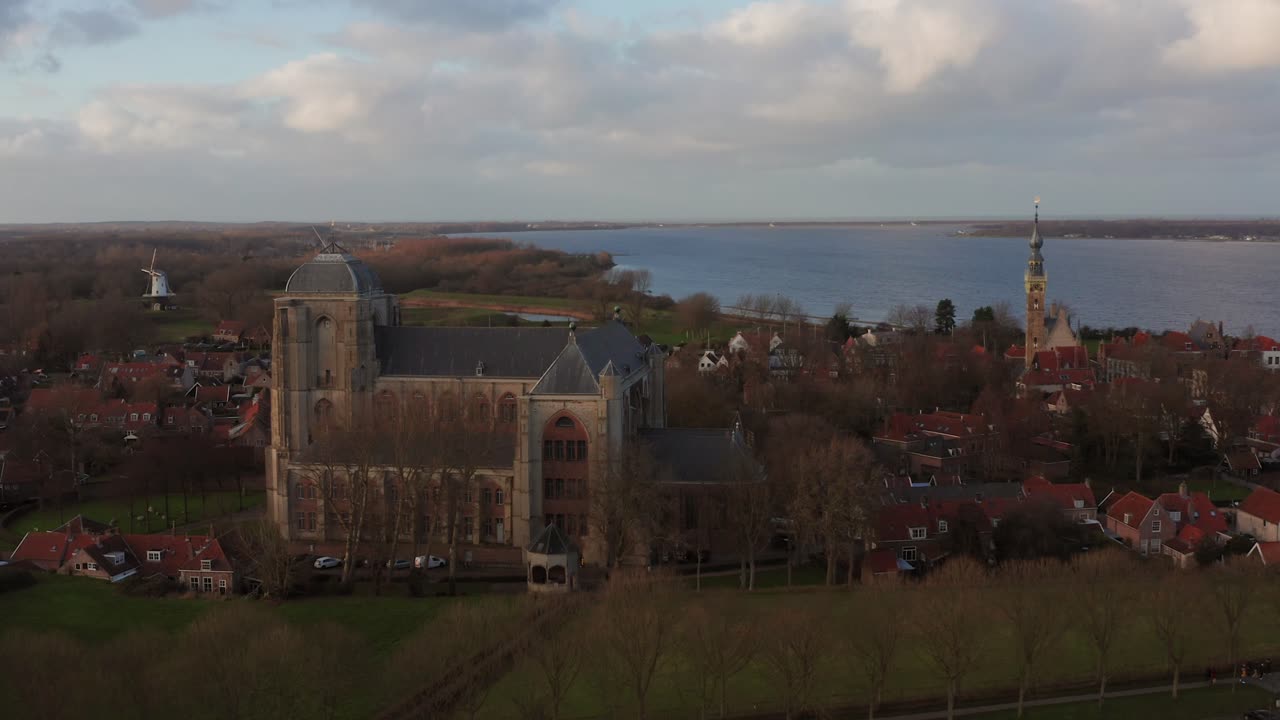 The big historical church in the touristic village Veere, located in a beautiful landscape. Drone shot zooming out