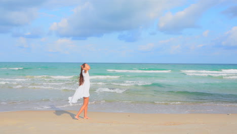 asian woman walking on the beach towards the sea by the water wearing a white sundress, raising hands up and turn around feel freedom on summer vacation