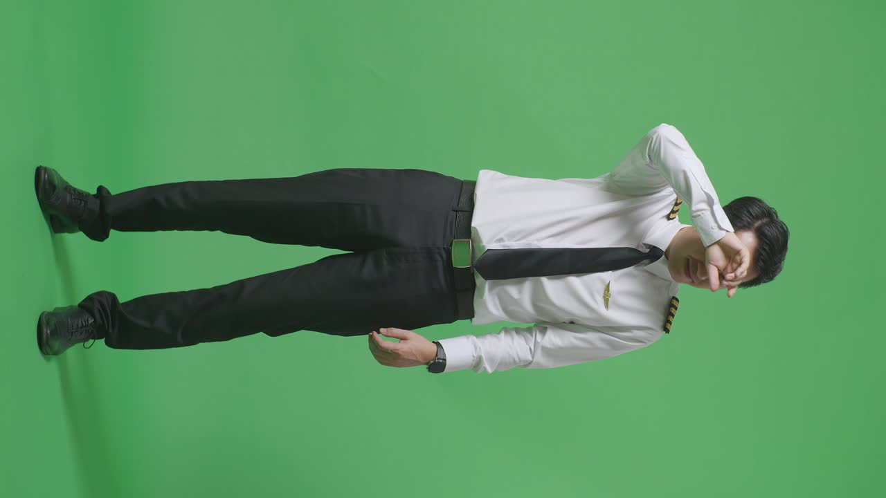 아시아 남성 조종사가 을 고 녹색 스크린 배경 스튜디오에 서있는 동안 피곤한 몸으로 가득 차 있습니다.