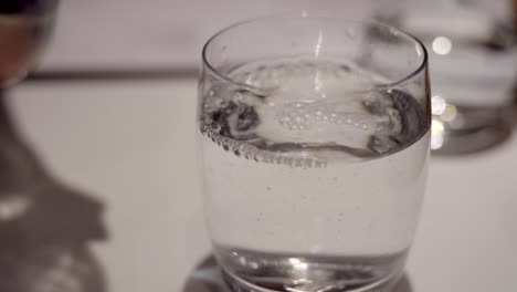 close up shot of water pouring into full glass in slow motion