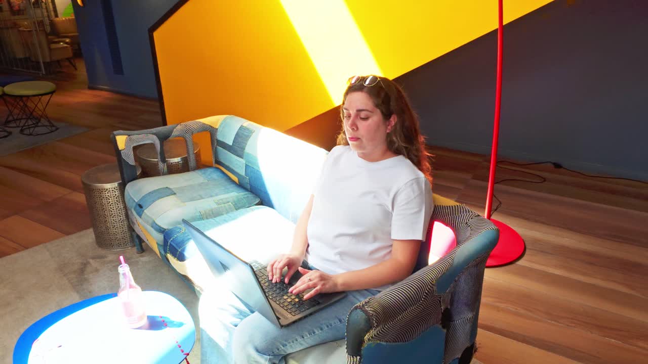 Donna che lavora da remoto al portatile in una moderna lobby di coworking