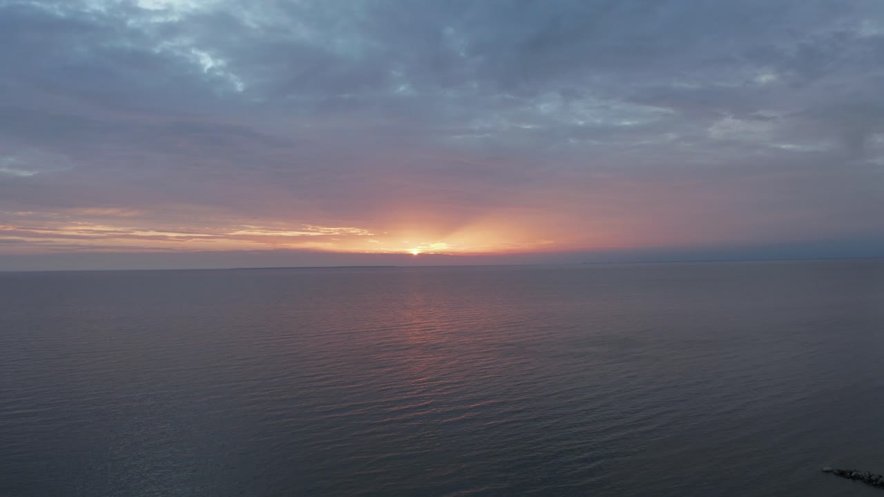 toma de dron de una tranquila puesta de sol en el mar, estonia, couds coloridos en 4k