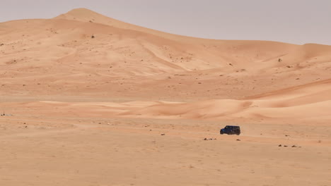 desert landscape with a vehicle navigating the vast, empty expanse of oman's empty quarters