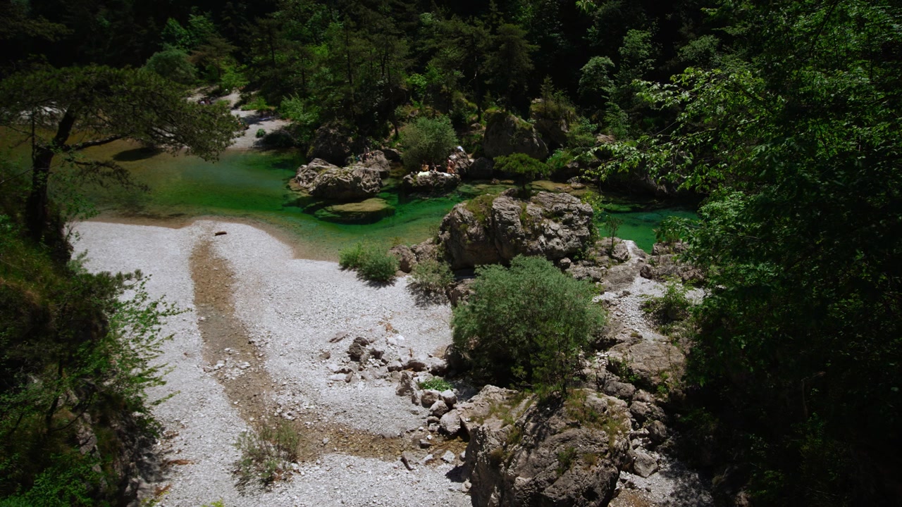 Pozza fluviale verde smeraldo all'interno di un ripido canyon roccioso con una fitta foresta estiva alle Pozze Smeraldine, Italia.
