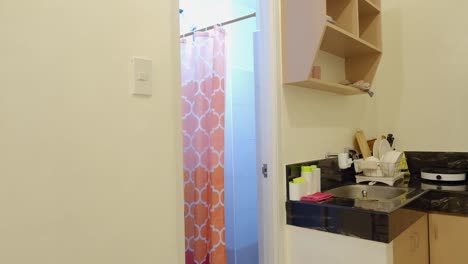 una joven saliendo de la ducha después de ponerse la ropa en el baño de su apartamento