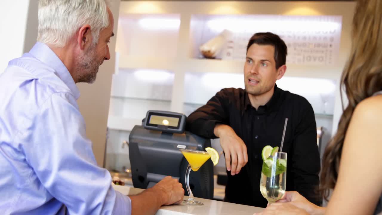 Barkeeper serviert Cocktails und unterhält sich mit Kunden