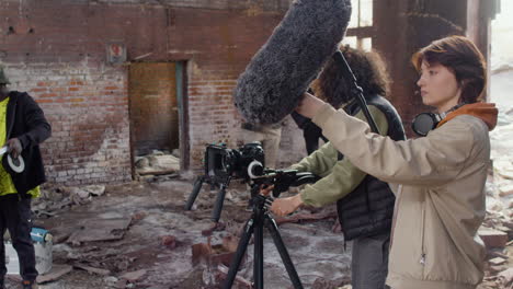 three production co workers getting ready to record in a ruined building