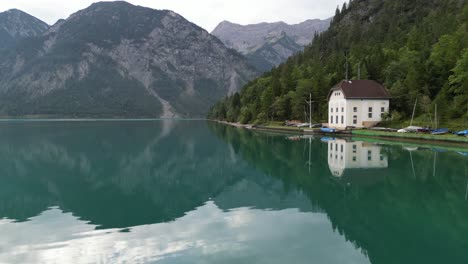 early morning over lake in tyrol austria clear still water drone aerial view 4k