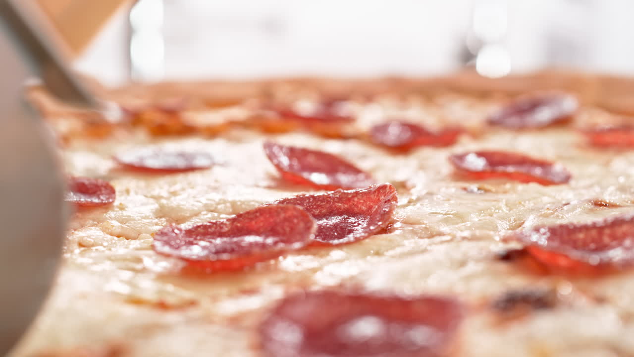 뉴욕 스타일의 페페로니 피자가 슬로모션과 매크로로 피자 커터로 잘라져 있습니다.