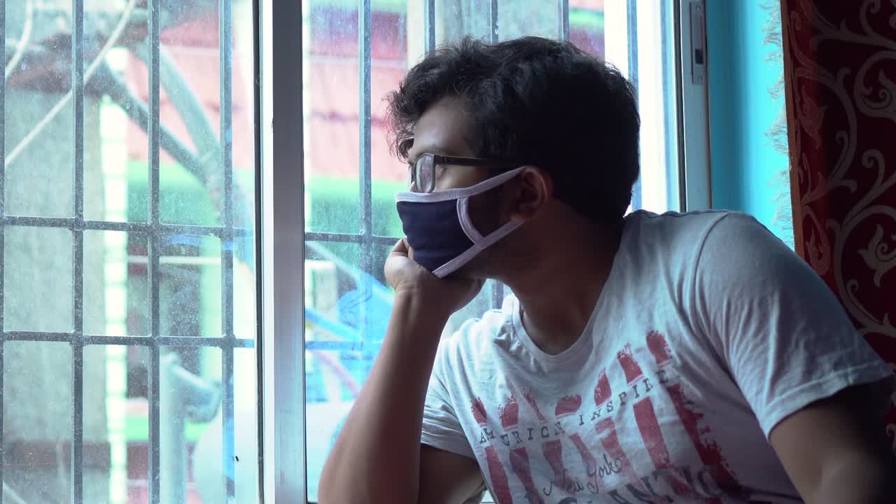 covid-19 코로나 바이러스 잠금, 자기 격리 및 사회적 거리로 인해 밖을 내다보는 창문 근처에 집에 앉아 있는 외로운 아시아 남성